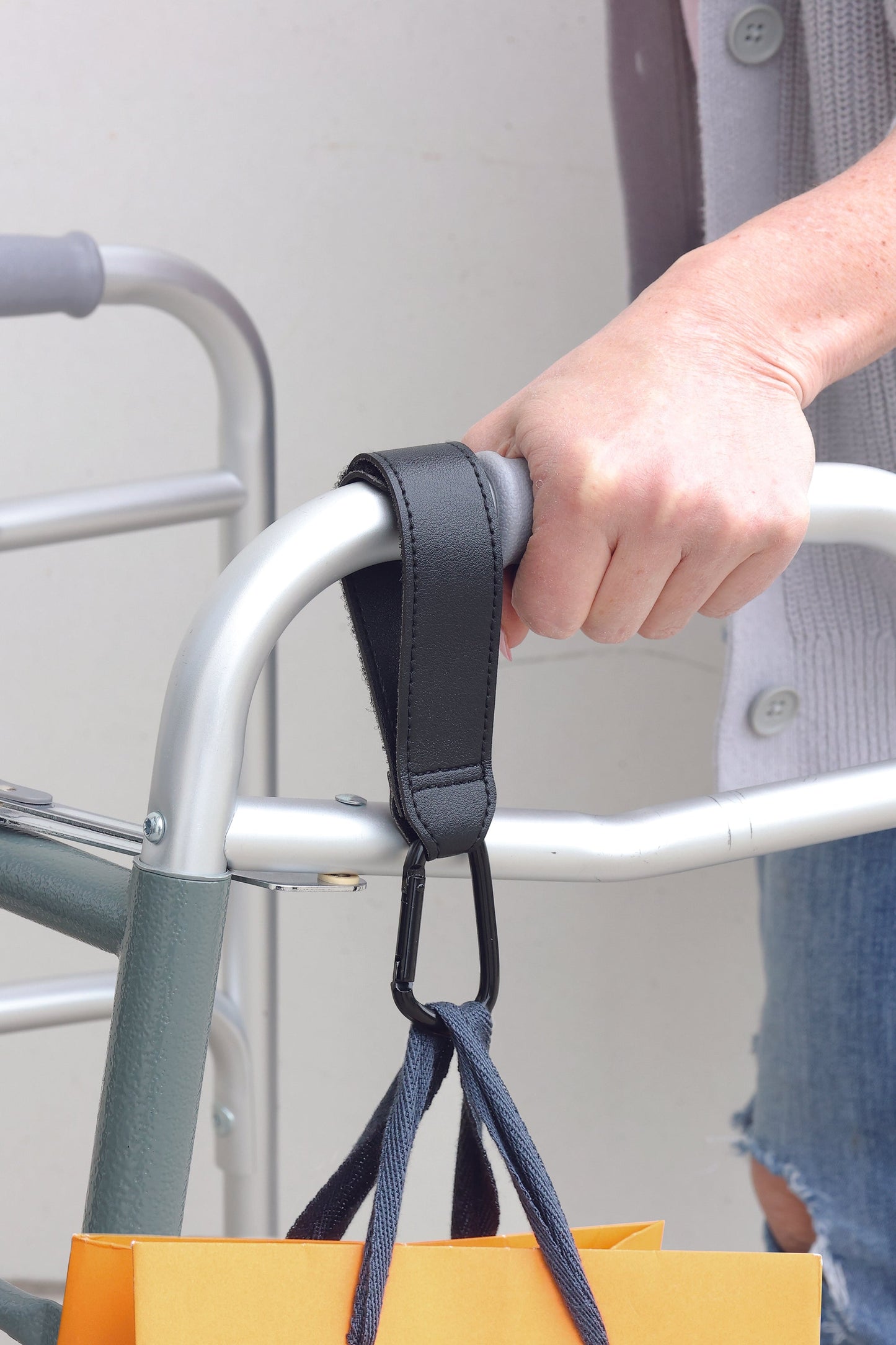 bag hook in use attached to a walker with a bag hanging off of it.