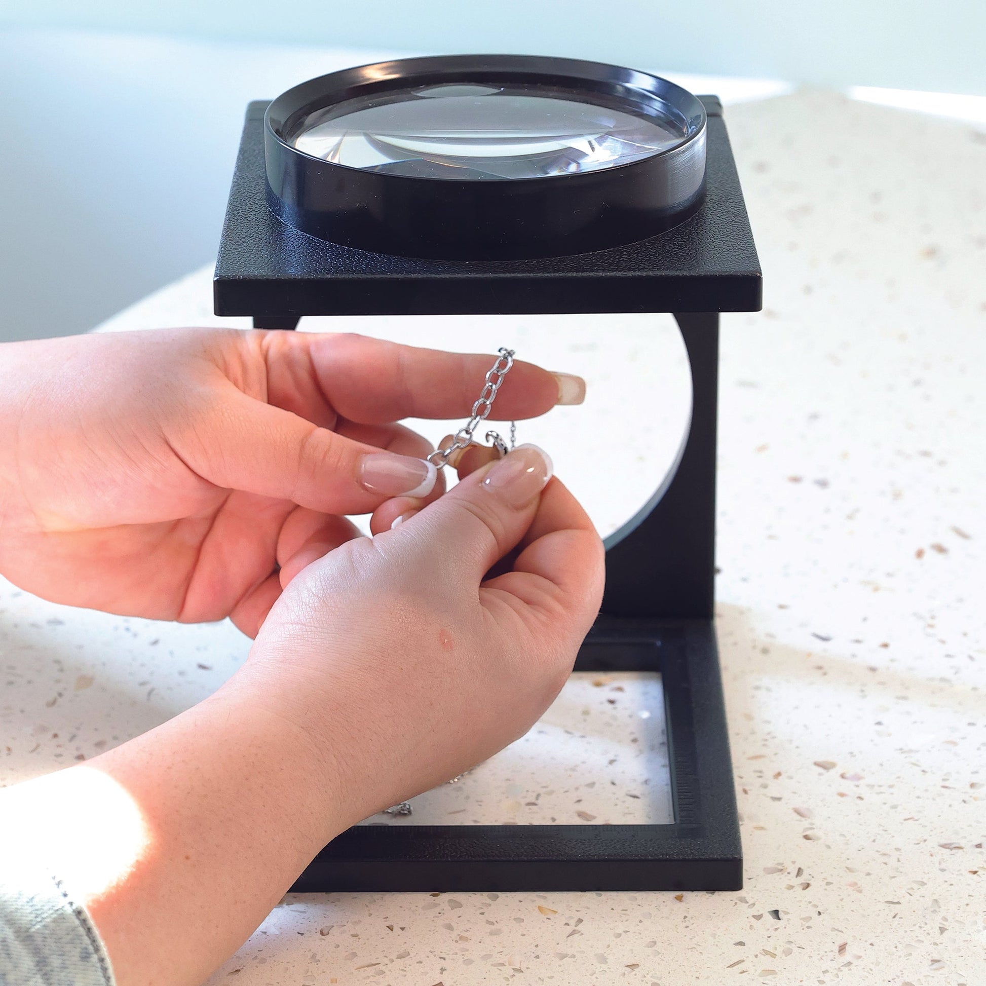 side view of the foldable magnifier in use while closing a necklace